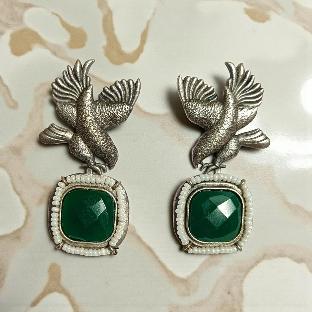 Rounded bird silhouette pairs brass with stone and bead detailing.