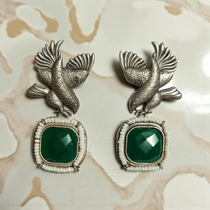 Rounded bird silhouette pairs brass with stone and bead detailing.