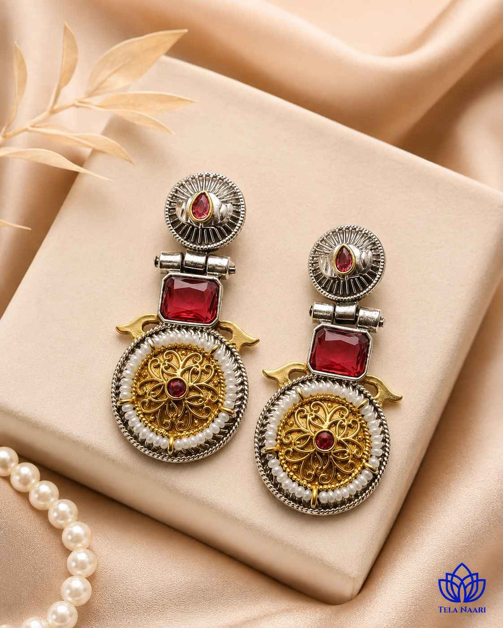 Red tones brighten the dual-tone surface of this statement earring.