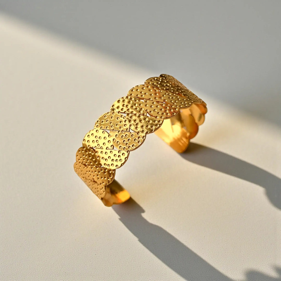 Sleek silhouette pairs a scallop pattern with a gold finish.