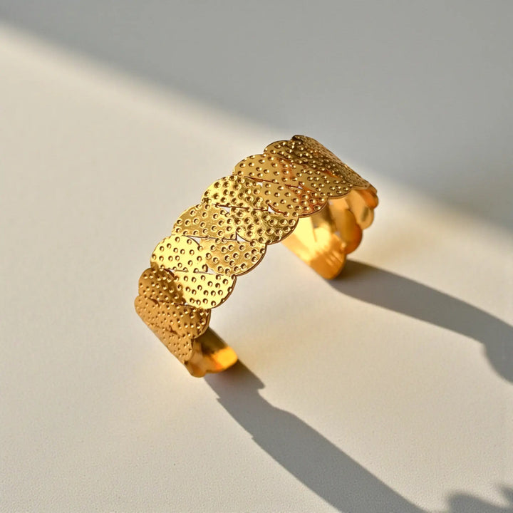 Sleek silhouette pairs a scallop pattern with a gold finish.