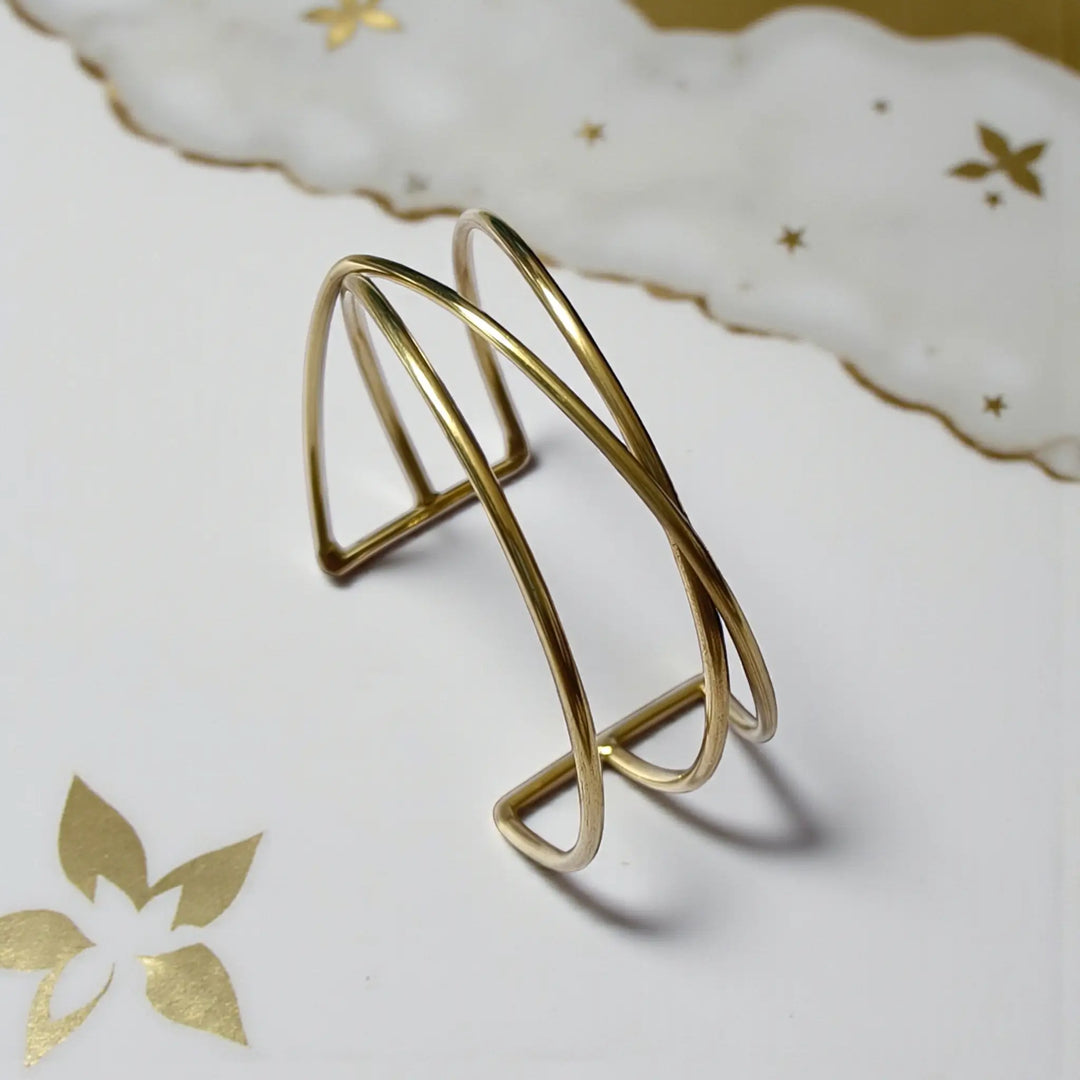 Polished surface highlights the sculpted structure of this brass cuff.