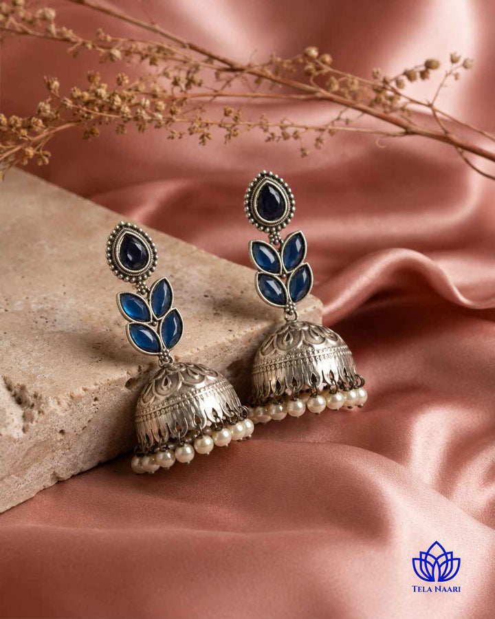 Graceful jhumka silhouette defines this blue silver-plated earring design.