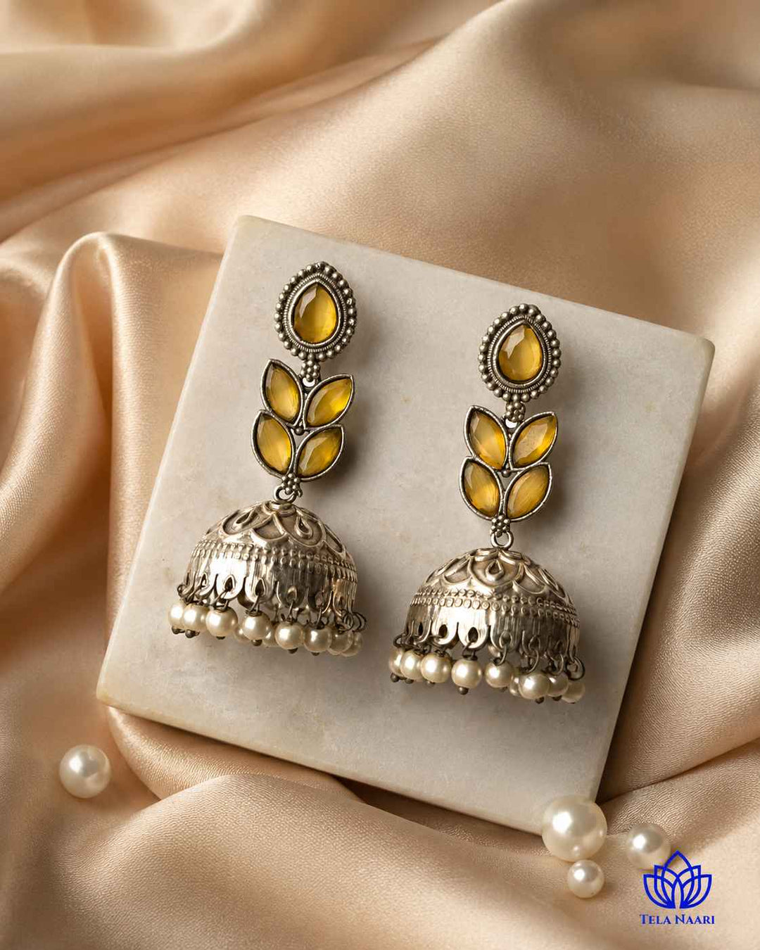 Brass construction supports the graceful jhumka silhouette of this earring.