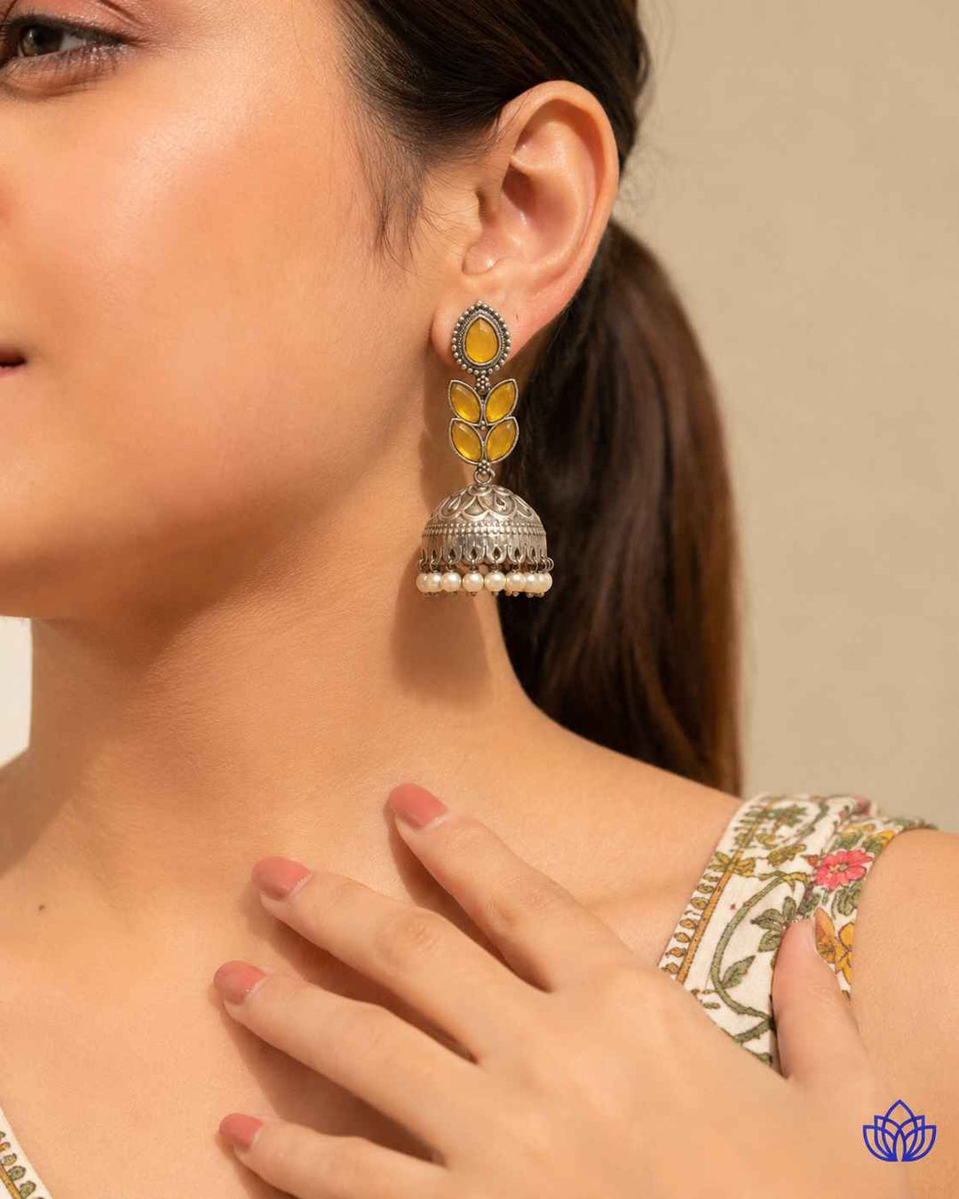 Graceful jhumka silhouette pairs silver-plated brass with a yellow accent.