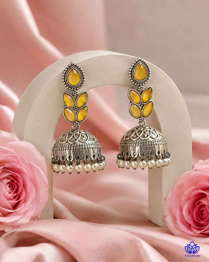 Delicate stone work highlights the yellow tones of this jhumka earring.