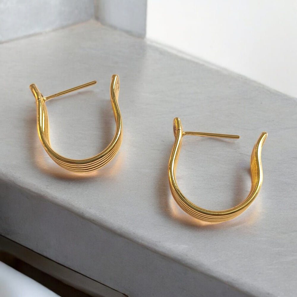 Brass construction supports the chunky hoop design of this earring.