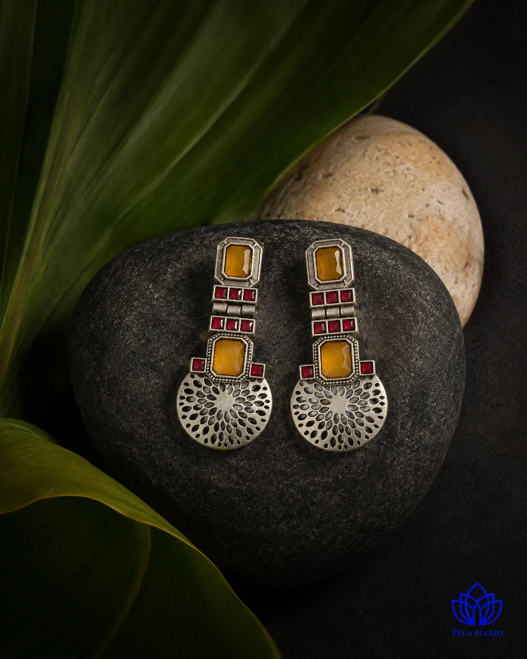 Striking amber and ruby tones shape this statement earring.
