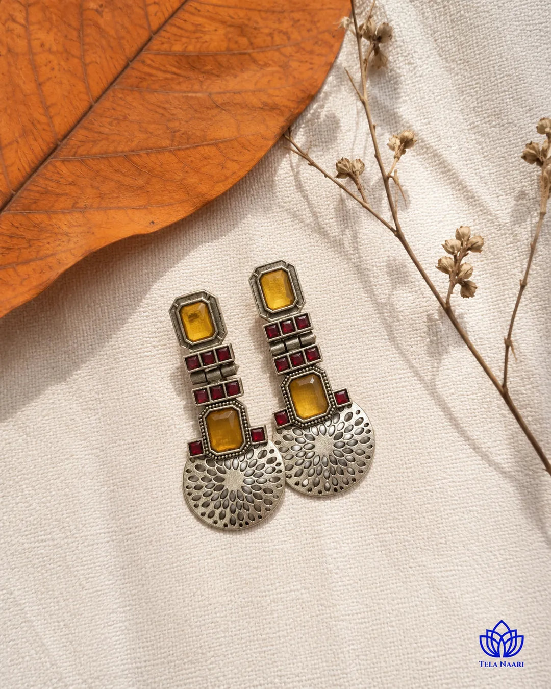Contemporary silhouette pairs amber tones with oxidised silver.