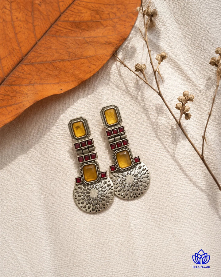 Contemporary silhouette pairs amber tones with oxidised silver.